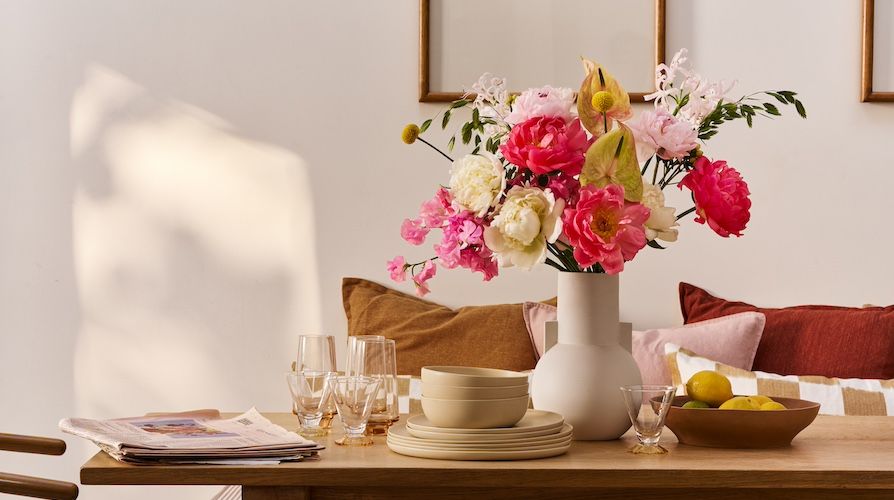 A bouquet of pink, coral and white peonies on a wooden table