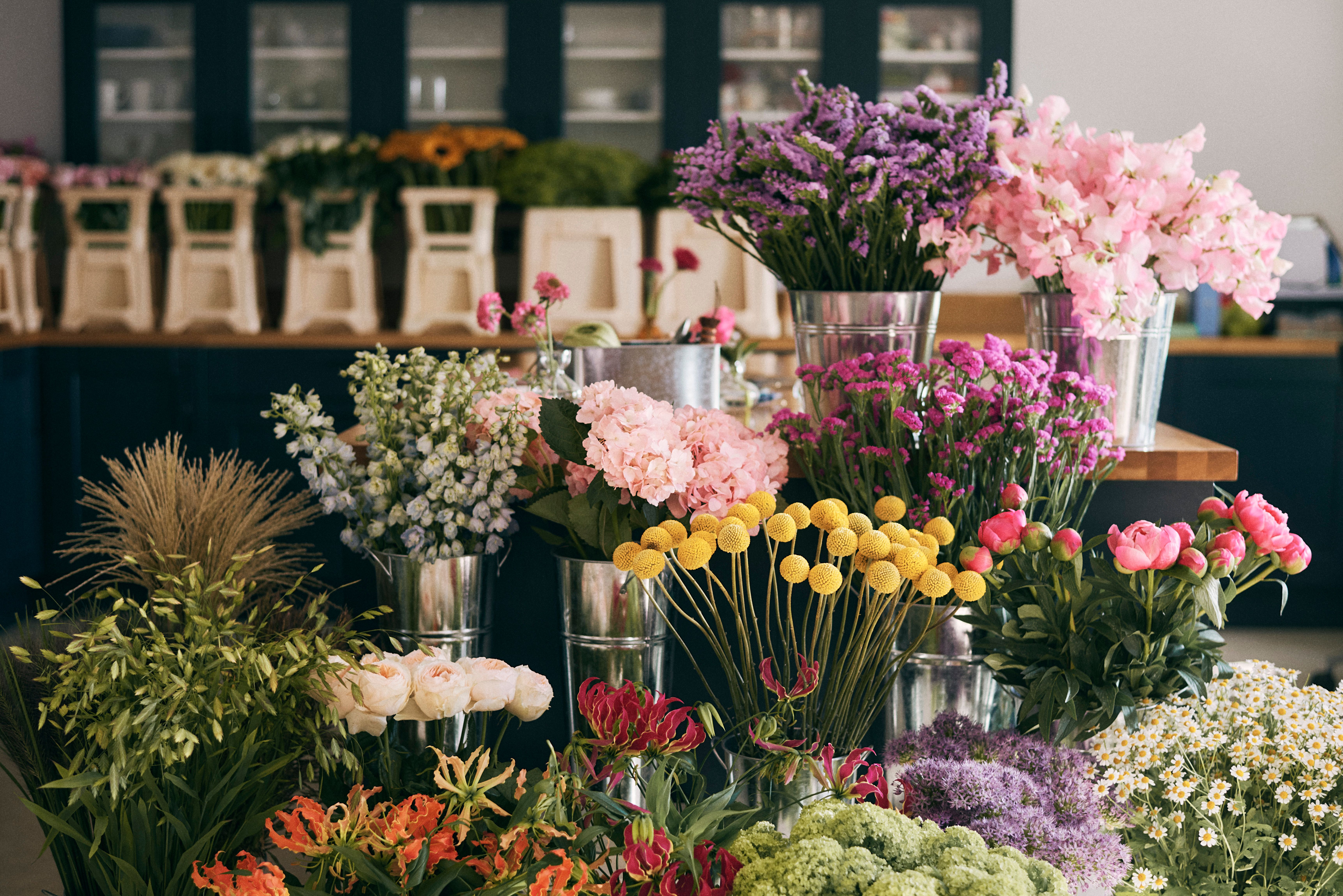 A selection of flowers in silver buckets, from pink peonies to purple alliums
