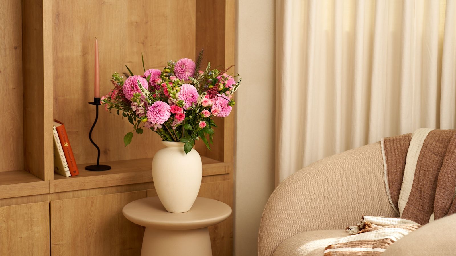 A mixed bouquet of pink dahlias and spray roses in a white vase