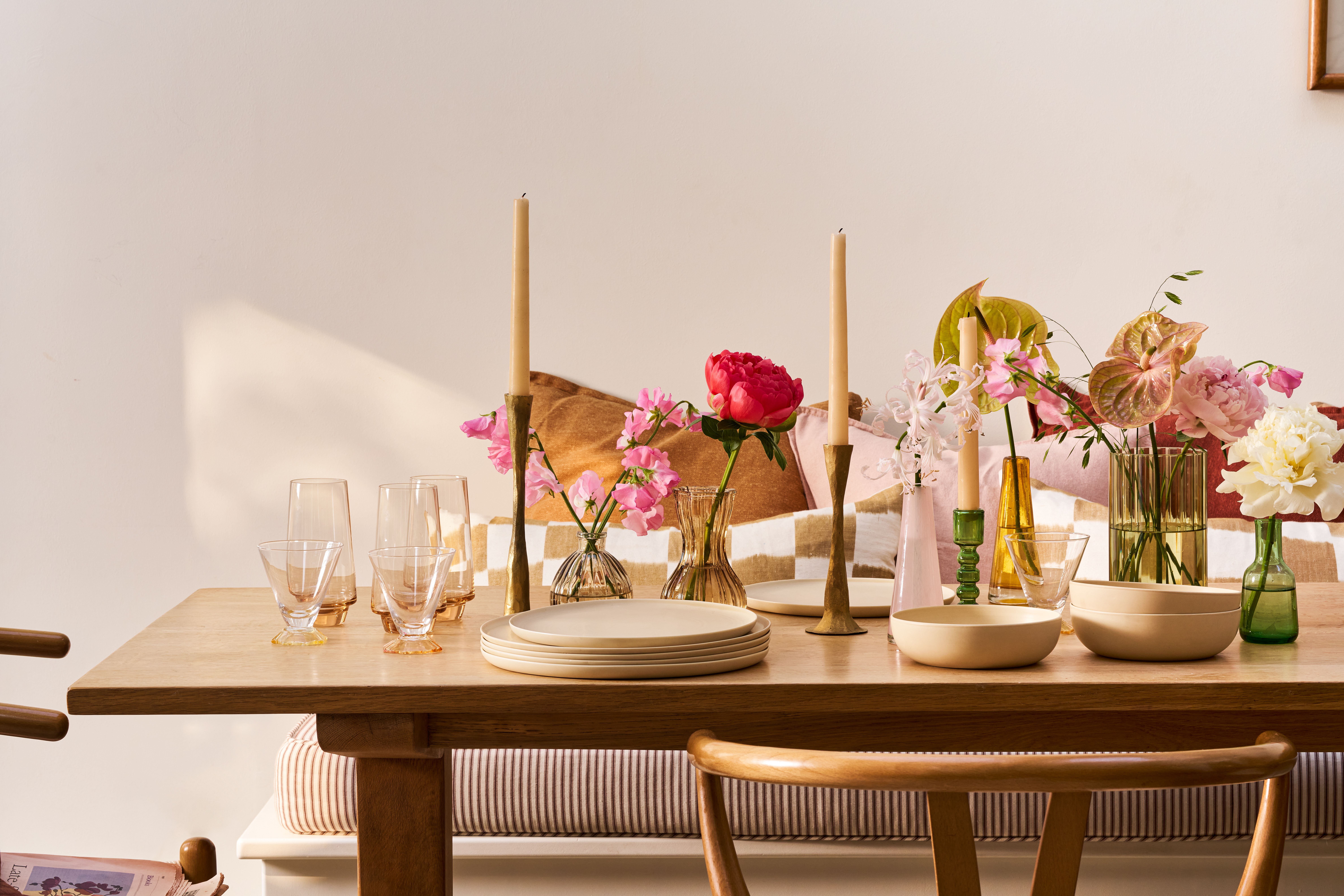 A table set with bud vases, candlesticks and crockery