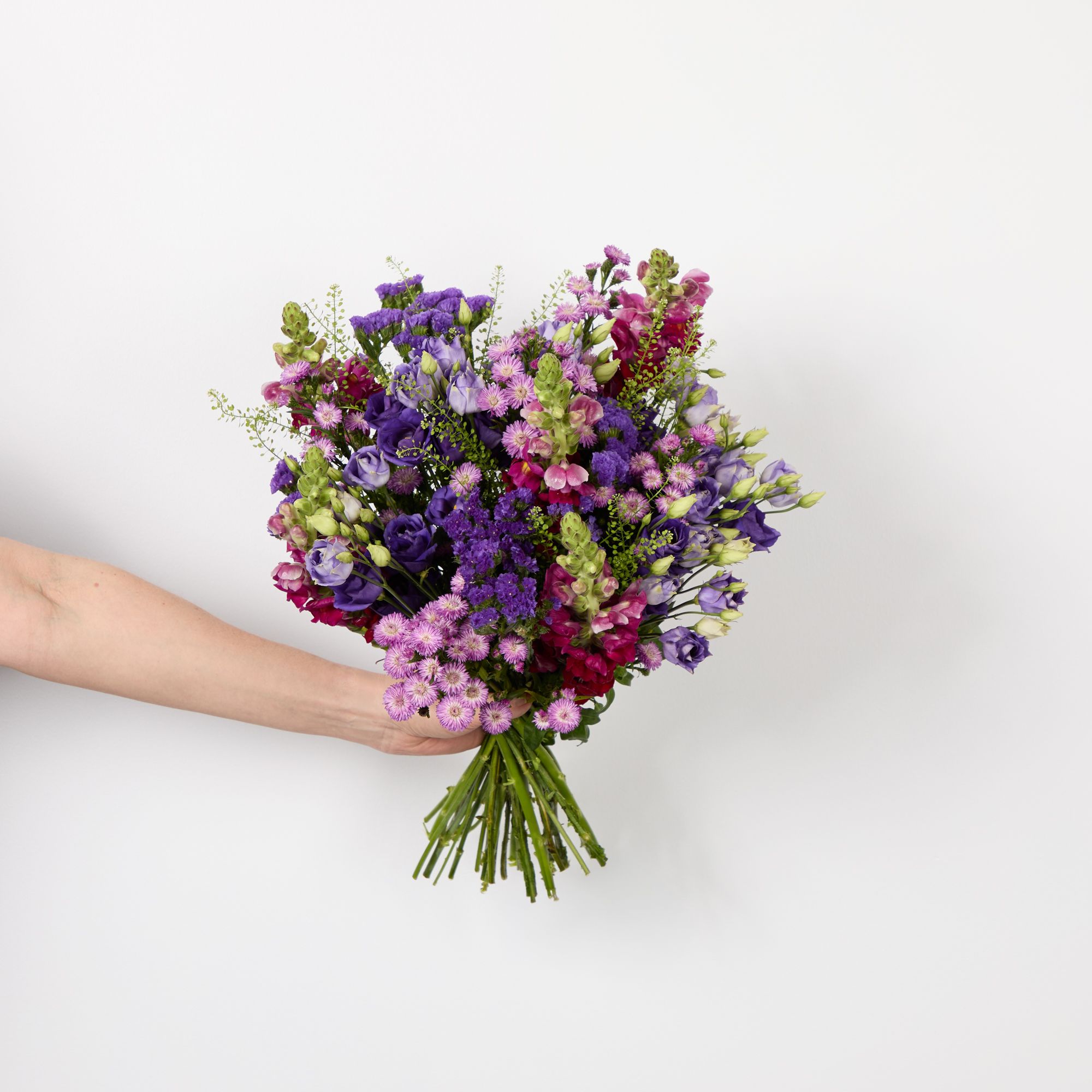 Purple lisianthus, cerise asters, burgundy antirrhinums, purple statice and greenbell