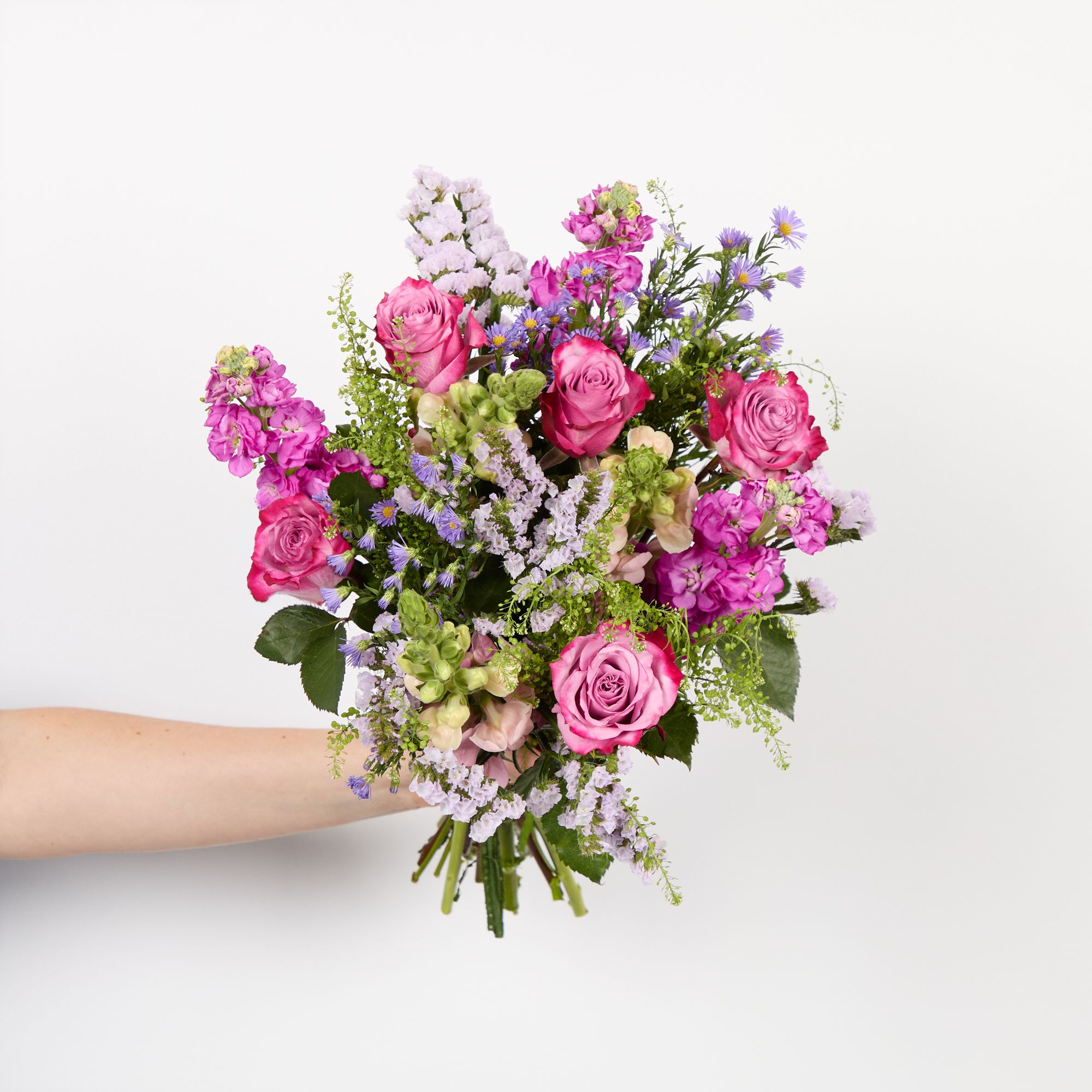 Pink antirrhinums, dark pink stocks, purple asters, 'Deep Purple' roses, lilac statice and greenbell