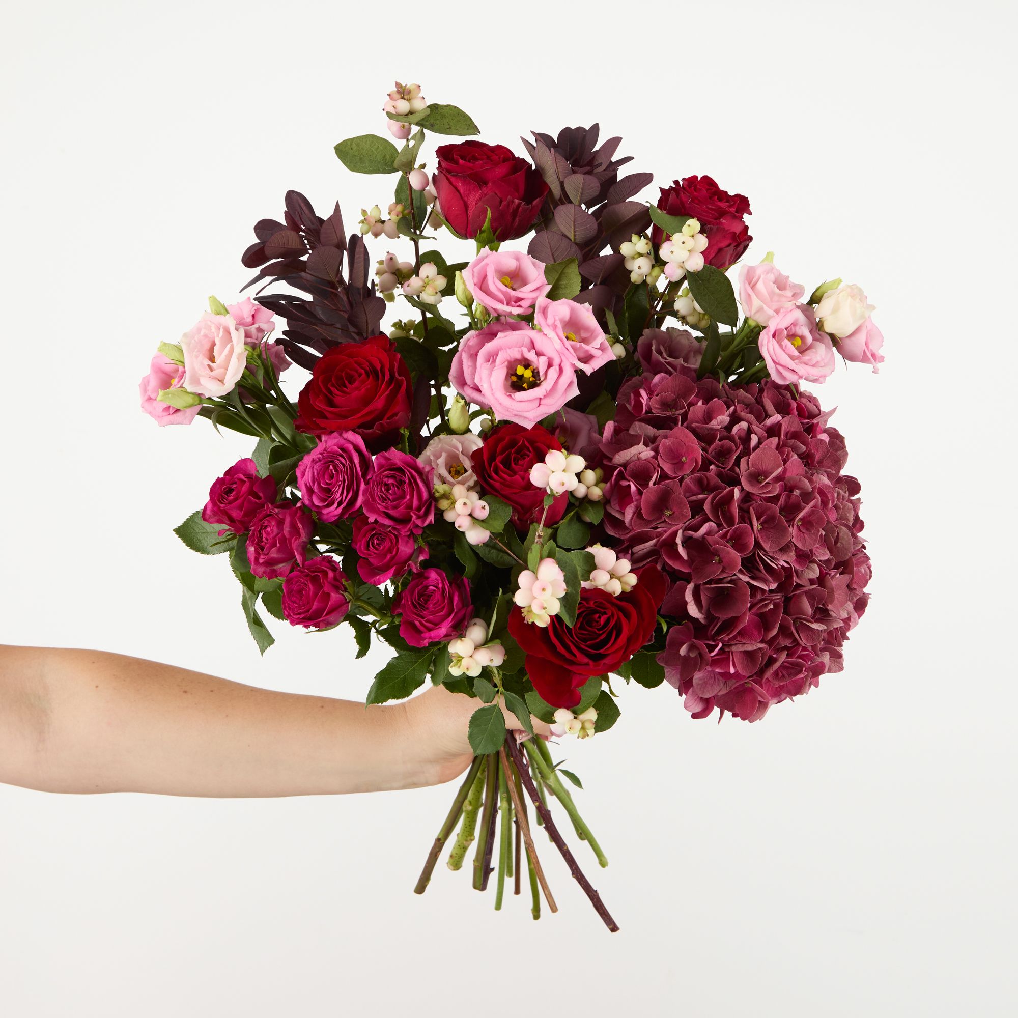 Antique red hydrangea, ‘Cheyenne’ spray roses, pink snowberries, pink lisianthus, red roses and cotinus