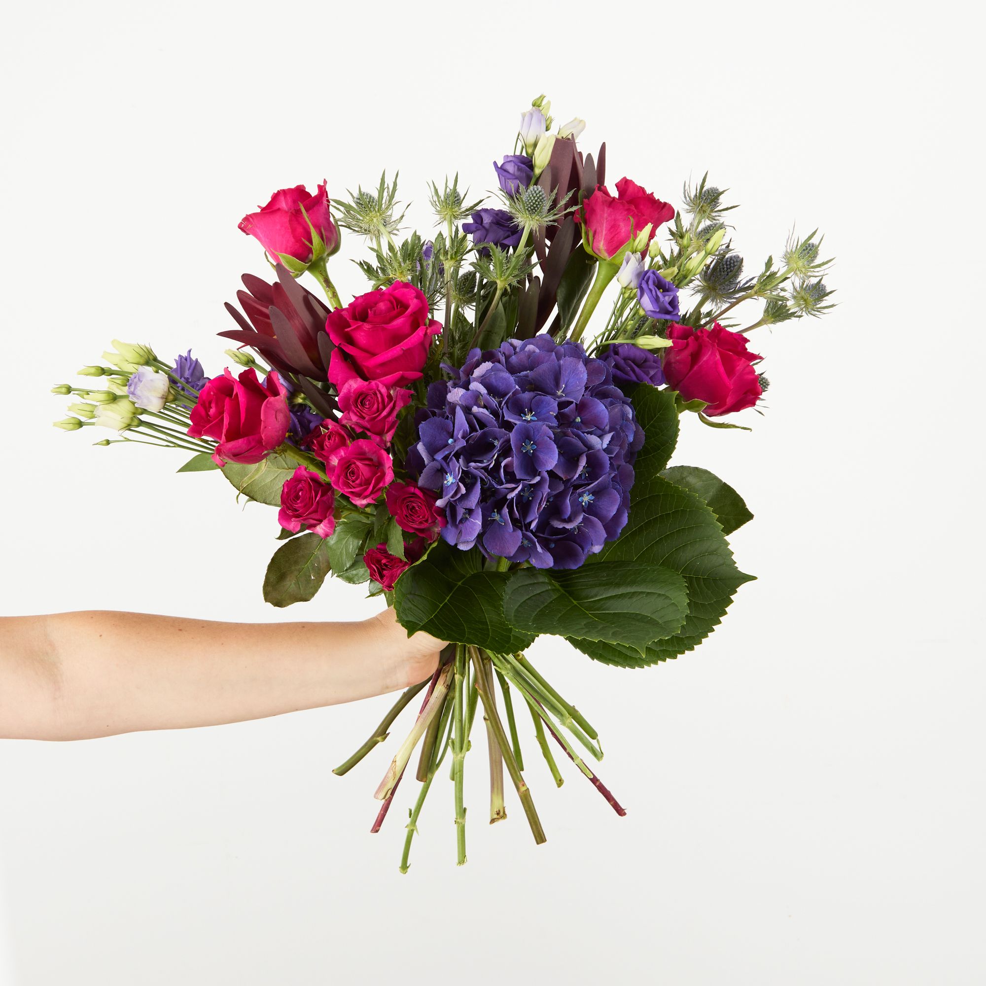 Purple hydrangea, purple lisianthus, blue eryngium, cerise roses, ‘Safari Sunset’ leucodendron and cerise spray roses