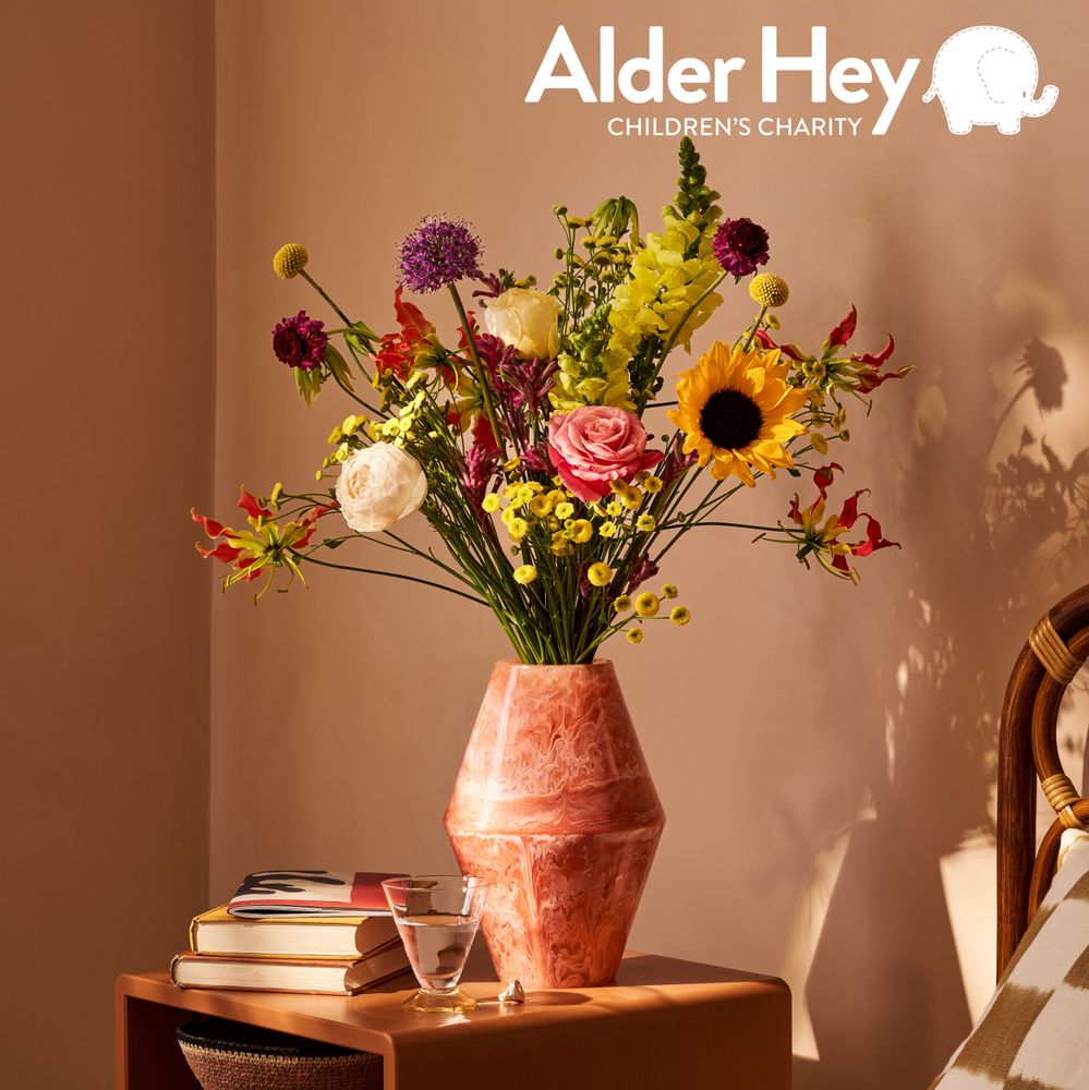A bouquet of roses, sunflowers and allliums. The picture has the Alder Hey logo in the corner.
